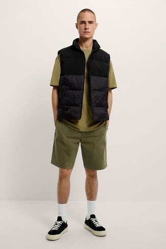 Sommer Outfits Herren 2024: Kombinieren Sie eine schwarze gesteppte ärmellose Jacke mit olivgrünen Shorts für einen bequemen Alltags-Look. Vervollständigen Sie Ihr Look mit schwarzen und weißen Segeltuch niedrigen Sneakers. Was für eine coole Sommer-Look Idee!