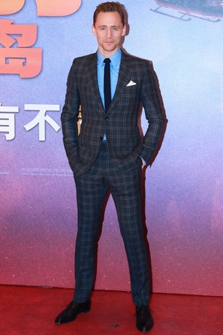 Tom Hiddleston trägt dunkelgrauer Anzug mit Karomuster, blaues Businesshemd, schwarze Leder Oxford Schuhe, dunkelblaue Strick Krawatte