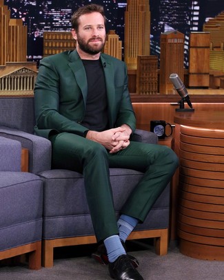 Armie Hammer trägt dunkelgrüner Anzug, schwarzer Pullover mit einem Rundhalsausschnitt, schwarze Leder Oxford Schuhe, blaue Socken