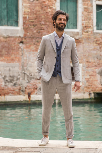 Grauen Anzug kombinieren – 1200+ Herren Outfits warm Wetter: Tragen Sie einen grauen Anzug und einen dunkelblauen Pullunder für einen stilvollen, eleganten Look. Wählen Sie die legere Option mit weißen Segeltuch niedrigen Sneakers.