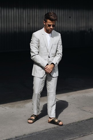 Dunkelgrauen Anzug kombinieren – 12 Casual Herren Outfits: Kombinieren Sie einen dunkelgrauen Anzug mit einem weißen T-Shirt mit einem Rundhalsausschnitt für Ihren Bürojob. Wenn Sie nicht durch und durch formal auftreten möchten, ergänzen Sie Ihr Outfit mit dunkelgrünen Ledersandalen.