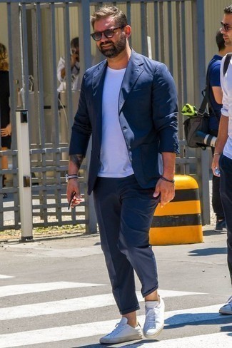 dunkelblauer Anzug, weißes T-Shirt mit einem Rundhalsausschnitt, weiße Leder niedrige Sneakers, graue Sonnenbrille für Herren