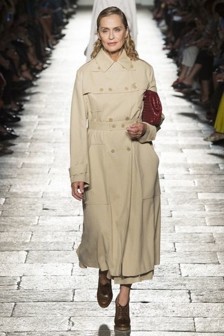 Lauren Hutton trägt beige Trenchcoat, braune Schnürstiefeletten aus Leder, dunkelrote Leder Clutch