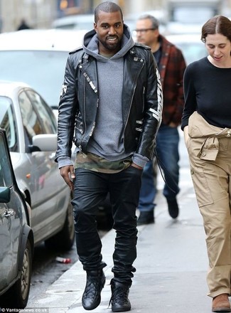 Kanye West trägt schwarze bedruckte Leder Bikerjacke, grauer Pullover mit einem Kapuze, olivgrünes Camouflage T-Shirt mit einem Rundhalsausschnitt, schwarze Jeans
