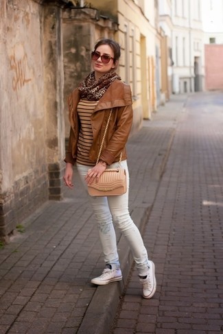 rotbraune Leder Bikerjacke, beige horizontal gestreifter Pullover mit einem Rundhalsausschnitt, weiße bedruckte enge Jeans, weiße niedrige Sneakers für Damen
