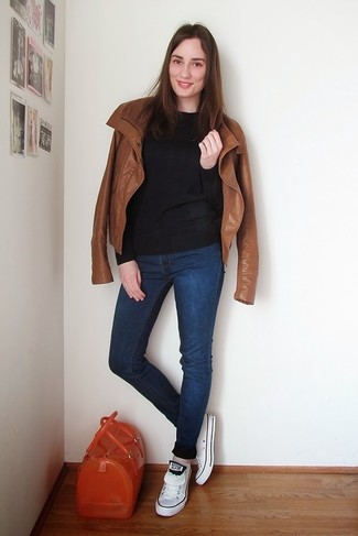 rotbraune Leder Bikerjacke, schwarzer Pullover mit einem Rundhalsausschnitt, dunkelblaue enge Jeans, weiße niedrige Sneakers für Damen
