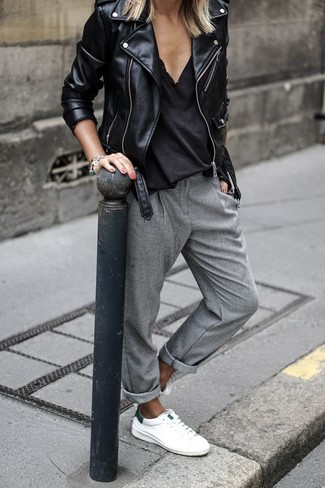 schwarze Leder Bikerjacke, schwarzes T-Shirt mit einem V-Ausschnitt, graue Karottenhose, weiße Leder Clutch für Damen