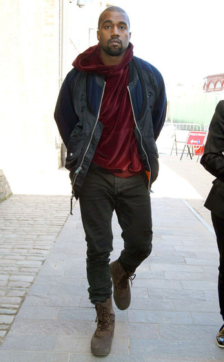 Kanye West trägt dunkelblaue Bomberjacke, dunkelroter Samtpullover mit einem kapuze, schwarze Jeans, dunkelbraune Winterschuhe