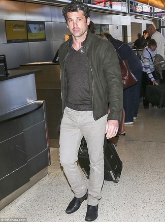 Patrick Dempsey trägt olivgrüne Leder Bomberjacke, grauer Pullover mit einem V-Ausschnitt, hellbeige Jeans, schwarze Chelsea-Stiefel aus Leder