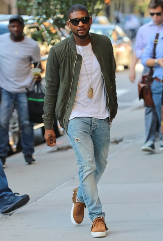 Usher trägt olivgrüne Bomberjacke, weißes T-Shirt mit einem Rundhalsausschnitt, hellblaue Jeans mit Destroyed-Effekten, beige Chukka-Stiefel aus Wildleder
