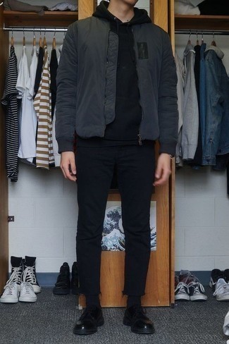 dunkelgraue Bomberjacke, schwarzer Pullover mit einem Kapuze, schwarze Jeans, schwarze Leder Derby Schuhe für Herren