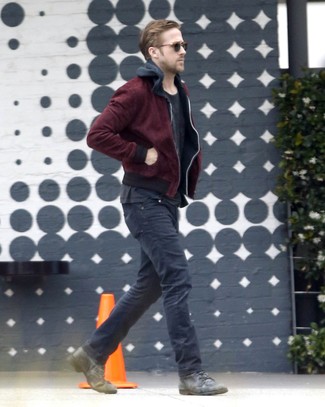 Ryan Gosling trägt dunkelrote Bomberjacke, schwarzer Pullover mit einem Kapuze, schwarzes T-Shirt mit einem Rundhalsausschnitt, schwarze Jeans