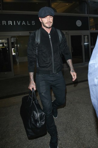 David Beckham trägt schwarze Wildleder Bomberjacke, schwarze Jeans, schwarze Sportschuhe, schwarze Schiebermütze