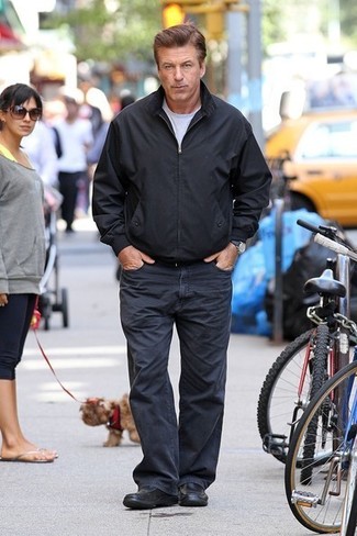 Alec Baldwin trägt schwarze Bomberjacke, graues T-Shirt mit einem Rundhalsausschnitt, dunkelblaue Jeans, schwarze Leder Slipper