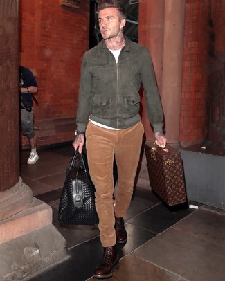 David Beckham trägt dunkelgraue Wildleder Bomberjacke, weißes T-Shirt mit einem Rundhalsausschnitt, rotbraune Cord Chinohose, dunkelbraune Lederfreizeitstiefel