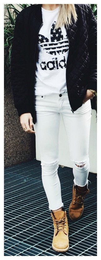 schwarze gesteppte Bomberjacke, weißes und schwarzes bedrucktes T-Shirt mit einem Rundhalsausschnitt, weiße enge Jeans mit Destroyed-Effekten, beige Nubuk flache Stiefel mit einer Schnürung für Damen