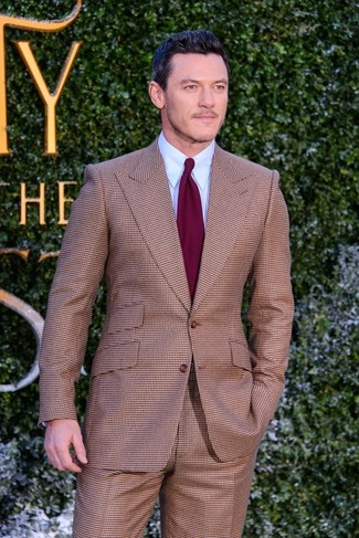Luke Evans trägt brauner Anzug mit Karomuster, hellblaues Businesshemd, dunkelrote Krawatte