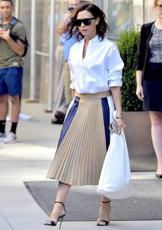 Victoria Beckham trägt weißes Businesshemd, hellbeige Falten Midirock aus Leder, schwarze Leder Sandaletten, weiße Shopper Tasche aus Leder