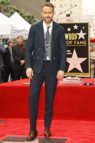 Ryan Reynolds trägt dunkelgrüne Cabanjacke, graue Wollweste, weißes Businesshemd, dunkelblaue Anzughose mit Schottenmuster