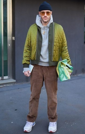 gelbgrüne Collegejacke, grauer Pullover mit einem Kapuze, braune Cord Chinohose, weiße Sportschuhe für Herren