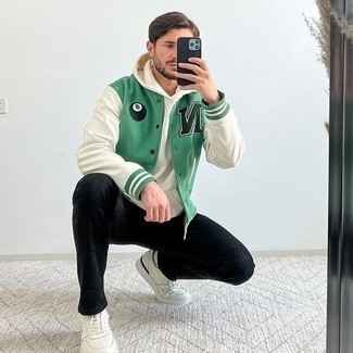 grüne Collegejacke, weißer Pullover mit einem Kapuze, schwarze Jeans, weiße Leder niedrige Sneakers für Herren