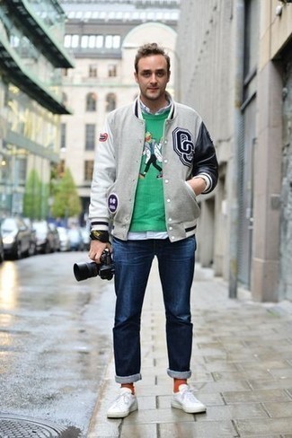graue Collegejacke, grüner bedruckter Pullover mit einem Rundhalsausschnitt, weißes Langarmhemd, dunkelblaue Jeans für Herren