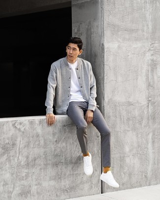 graue Collegejacke, weißes T-Shirt mit einem Rundhalsausschnitt, graue Chinohose, weiße Leder niedrige Sneakers für Herren