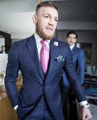 Conor McGregor trägt dunkelblauer vertikal gestreifter Dreiteiler, weißes Businesshemd, dunkelblaues gepunktetes Einstecktuch, rosa Anstecknadel mit Blumenmuster