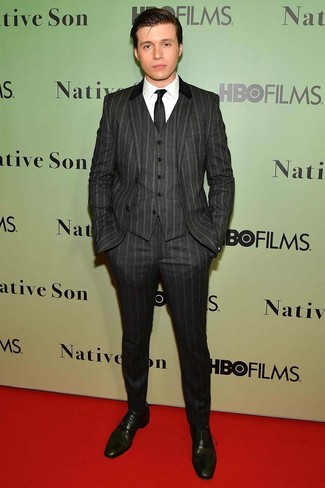 Nick Robinson trägt dunkelgrauer vertikal gestreifter Dreiteiler, weißes Businesshemd, olivgrüne Leder Oxford Schuhe, schwarze Krawatte