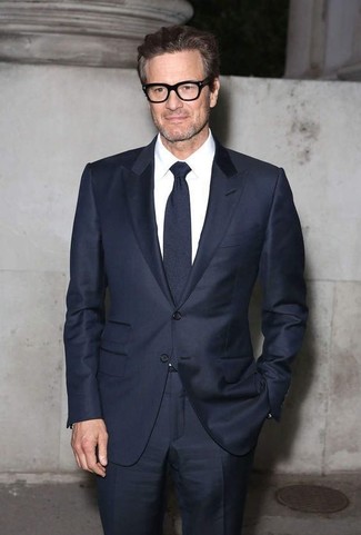 Colin Firth trägt dunkelblauer Anzug, weißes Businesshemd, dunkelblaue Krawatte
