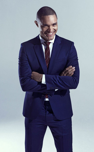 Trevor Noah trägt dunkelblauer Anzug, weißes Businesshemd, dunkelrote vertikal gestreifte Krawatte