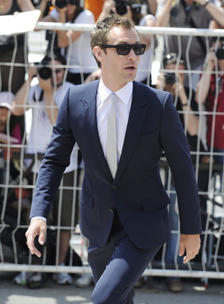 Jude Law trägt dunkelblauer Anzug, weißes Businesshemd, graue Krawatte