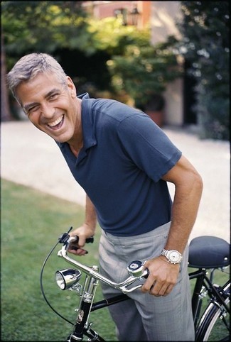 George Clooney trägt dunkelblaues Polohemd, graue Anzughose, silberne Uhr