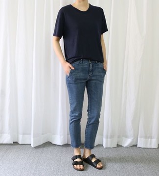 dunkelblaues T-Shirt mit einem Rundhalsausschnitt, dunkelblaue Jeans, schwarze flache Sandalen aus Leder für Damen