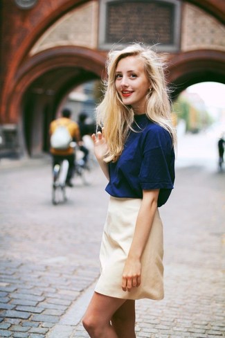Hellbeige Minirock kombinieren – 50 Damen Outfits: Um ein stilvolles, entspanntes Outfit zu erzielen, probieren Sie die Kombination aus einem dunkelblauen T-Shirt mit einem Rundhalsausschnitt und einem hellbeige Minirock.