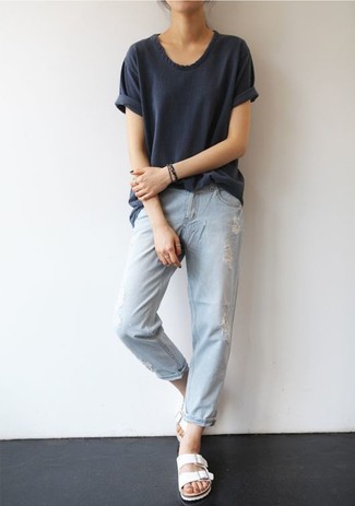 dunkelgraues T-Shirt mit einem Rundhalsausschnitt, hellblaue Boyfriend Jeans mit Destroyed-Effekten, weiße flache Sandalen aus Leder für Damen