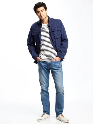 dunkelblaue Feldjacke, weißes und schwarzes horizontal gestreiftes T-Shirt mit einem Rundhalsausschnitt, blaue Jeans, weiße Leinenschuhe für Herren