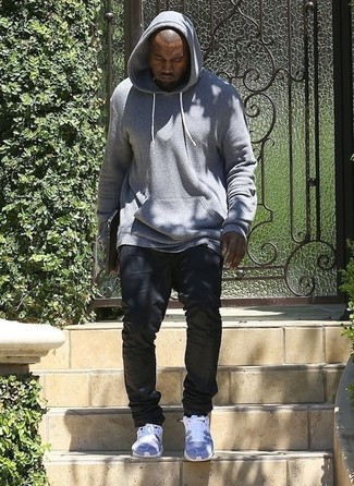 Kanye West trägt grauer Pullover mit einem Kapuze, schwarze Jeans, graue Sportschuhe