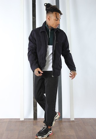 schwarze Harrington-Jacke, weißer und grüner Pullover mit einem Reißverschluss am Kragen, schwarze Jeans, schwarze Sportschuhe für Herren