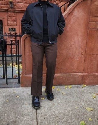 Herbst Outfits Herren 2024: Entscheiden Sie sich für eine schwarze Harrington-Jacke und eine dunkelbraune Chinohose für einen bequemen Alltags-Look. Setzen Sie bei den Schuhen auf die klassische Variante mit schwarzen Leder Derby Schuhen. Ein insgesamt sehr cooles Übergangs-Outfit.