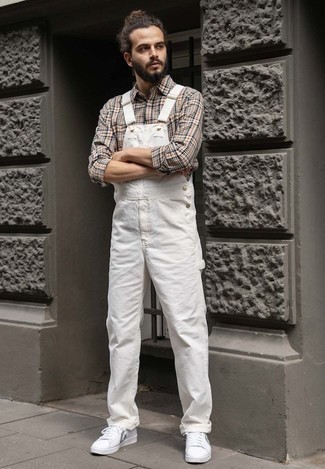 Jeans Latzhose kombinieren – 54 Herren Outfits: Ein hellbeige Langarmhemd mit Schottenmuster und eine Jeans Latzhose sind eine perfekte Outfit-Formel für Ihre Sammlung. Fügen Sie weißen bedruckten Segeltuch niedrige Sneakers für ein unmittelbares Style-Upgrade zu Ihrem Look hinzu.