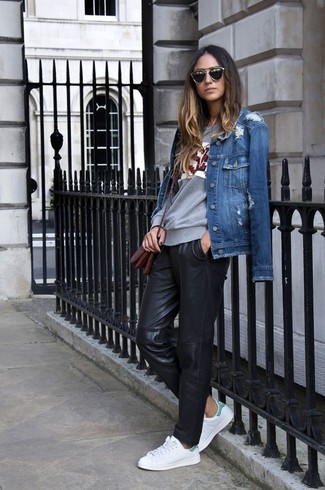 blaue Jeansjacke, graues bedrucktes Langarmshirt, schwarze Freizeithose aus Leder, weiße niedrige Sneakers für Damen