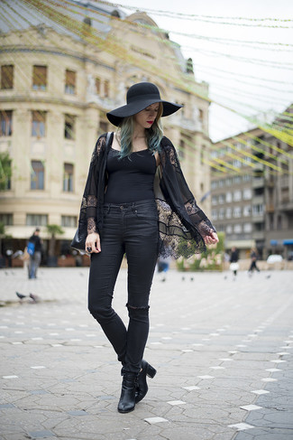 schwarzer Spitzekimono, schwarzes Trägershirt, schwarze enge Jeans mit Destroyed-Effekten, schwarze Leder Stiefeletten mit Ausschnitten für Damen