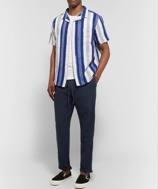 weißes und dunkelblaues vertikal gestreiftes Kurzarmhemd, weißes T-Shirt mit einem Rundhalsausschnitt, dunkelblaue Chinohose, schwarze Slip-On Sneakers aus Segeltuch für Herren