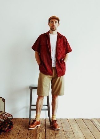 Herren Outfits 2022: Tragen Sie ein rotes vertikal gestreiftes Kurzarmhemd und beige Shorts, um einen lockeren, aber dennoch stylischen Look zu erhalten. Rotbraune Leder Derby Schuhe sind eine einfache Möglichkeit, Ihren Look aufzuwerten.