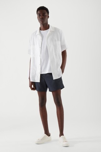 Dunkelblaue Shorts kombinieren – 804+ Herren Outfits: Erwägen Sie das Tragen von einem weißen Kurzarmhemd und dunkelblauen Shorts, um einen lockeren, aber dennoch stylischen Look zu erhalten. Vervollständigen Sie Ihr Look mit weißen Segeltuch niedrigen Sneakers.