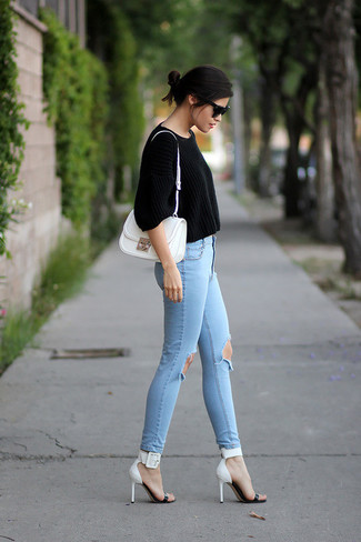 schwarzer kurzer Pullover, hellblaue enge Jeans mit Destroyed-Effekten, weiße und schwarze Leder Sandaletten, weiße Satchel-Tasche aus Leder für Damen
