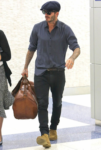 David Beckham trägt dunkelblaues bedrucktes Langarmhemd, schwarze Jeans, beige Wildlederfreizeitstiefel, braune Leder Reisetasche