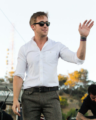 Ryan Gosling trägt weißes Langarmhemd, graue Wollanzughose, schwarzer Ledergürtel, schwarze Sonnenbrille