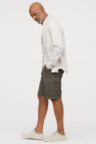 Sommer Outfits Herren 2024: Kombinieren Sie ein weißes Langarmhemd mit dunkelgrauen Shorts für ein Alltagsoutfit, das Charakter und Persönlichkeit ausstrahlt. Weiße Segeltuch niedrige Sneakers sind eine perfekte Wahl, um dieses Outfit zu vervollständigen. Dieses Outfit ist wunderbar für den Sommer geeignet.